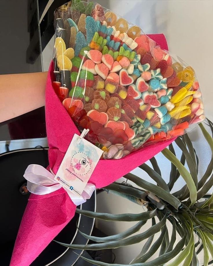 a bunch of candies sitting on top of a pink wrapper next to a potted plant