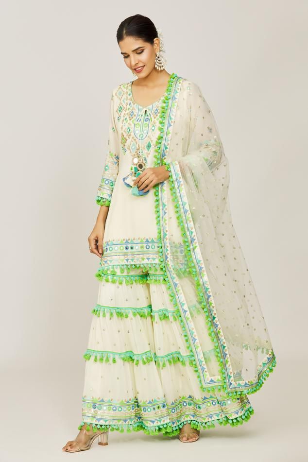 Ivory straight kurta with mirror, sequin, pompom and tassel details. Paired with a layered embroidered sharara and net embroidered dupatta.
Components: 3
Pattern: Embroidered
Type Of Work: Hand and machine embroidery
Neckline: Round
Sleeve Type: Three-quarter
Fabric: Kurta: Viscose, Sharara: Cotton Satin, Dupatta: Net
Color: Ivory
Other Details: 
Sequin and mirror embroidery
Sharara closure: Drawstring
Occasion: Mehendi and Haldi - Aza Fashions Festive Straight Kurta Sharara With Tassels, Festive Sharara With Tassels And Straight Kurta, Festive Kurta With Tassels, Festive Bollywood Kurta With Tassels, Diwali Anarkali Set With Straight Kurta And Tassels, Diwali Anarkali Set With Tassels And Straight Kurta, Traditional Anarkali Set With Tassels For Designer Wear, Off White Salwar Kameez With Mirror Work For Diwali, Embroidered Off White Palazzo Set For Festivals