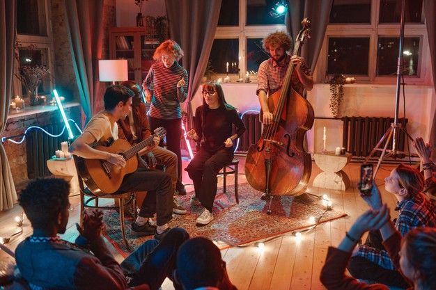 a group of people playing instruments in a living room with lights on the floor and windows