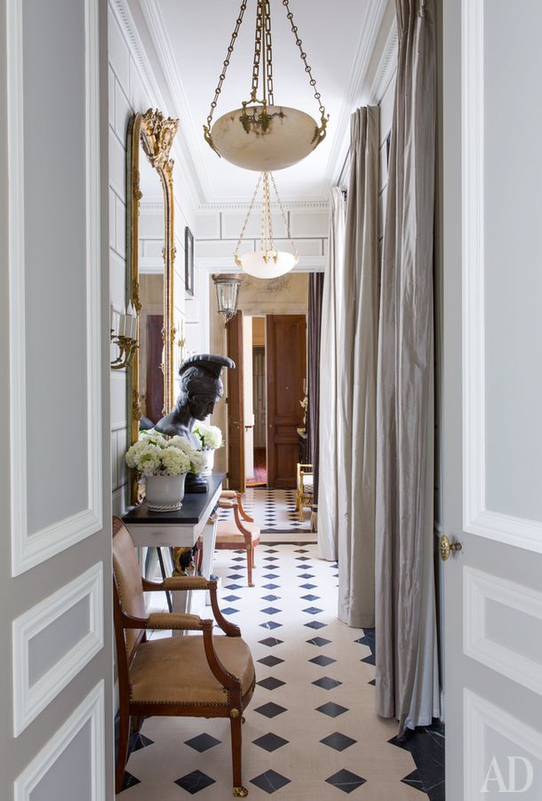 the hallway is decorated with black and white checkered flooring, chandelier, and antique furniture