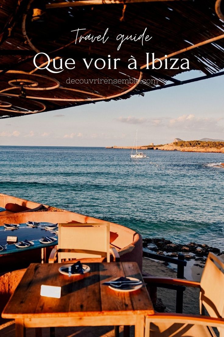 a wooden table sitting on top of a beach next to the ocean with boats in the water