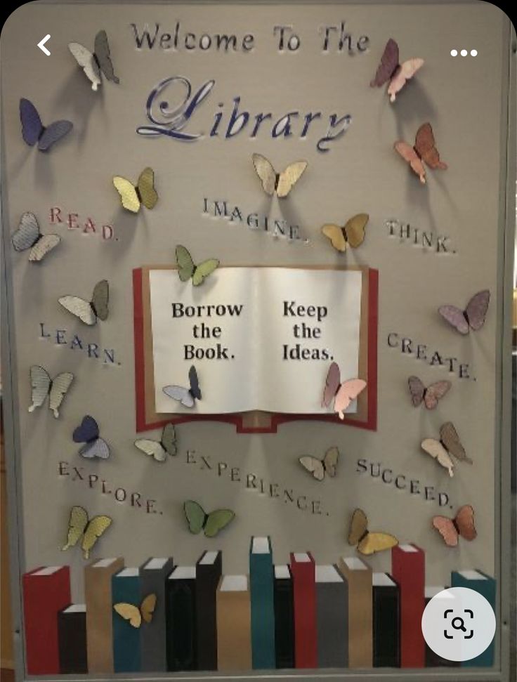 a library display with books and butterflies on the back wall, reading is welcome to the library