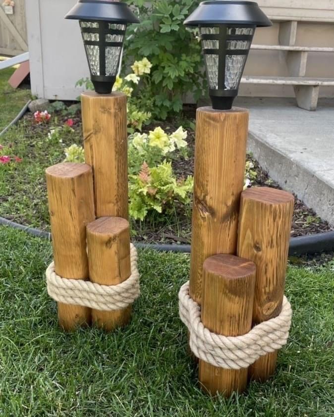 wooden logs are stacked on top of each other in the grass near a light pole