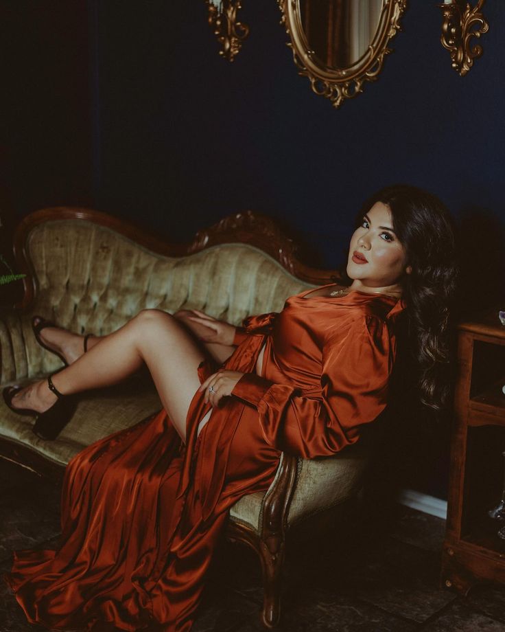 a woman in an orange dress sitting on a couch