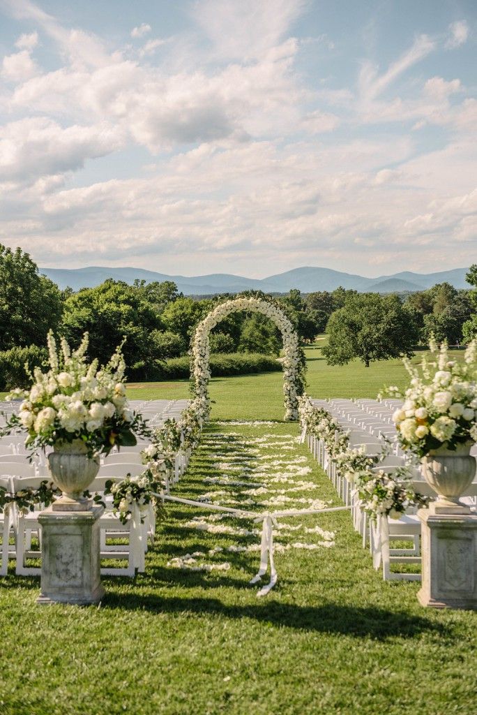 an outdoor ceremony set up with white chairs and flowers