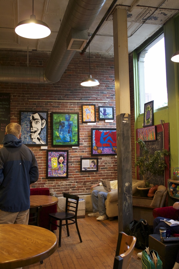 a man standing in front of a brick wall with paintings on it's walls