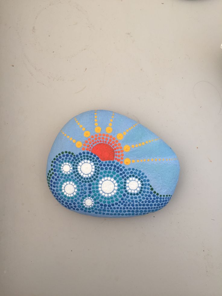 a painted rock sitting on top of a white table next to a clock and other items