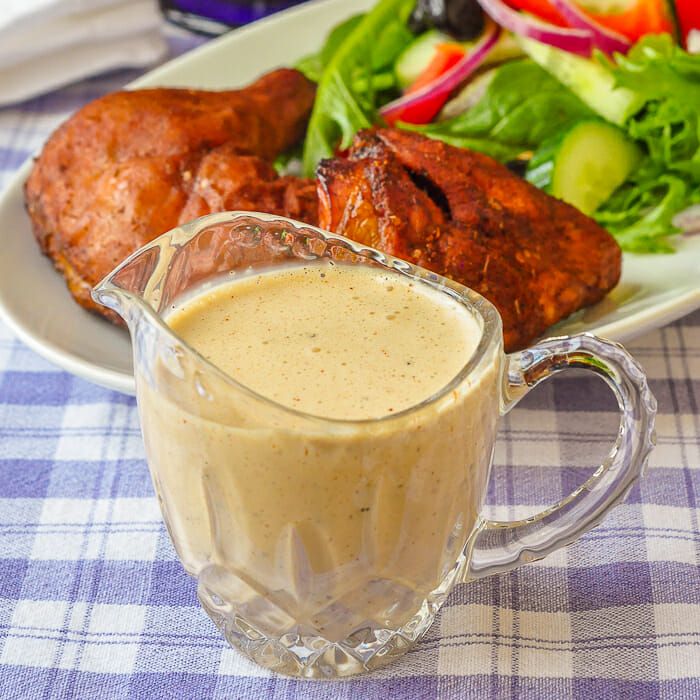 a glass pitcher filled with liquid next to a plate of meat and salad on a table