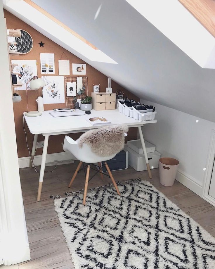 an attic bedroom with a desk and chair in front of the window, along with pictures on the wall