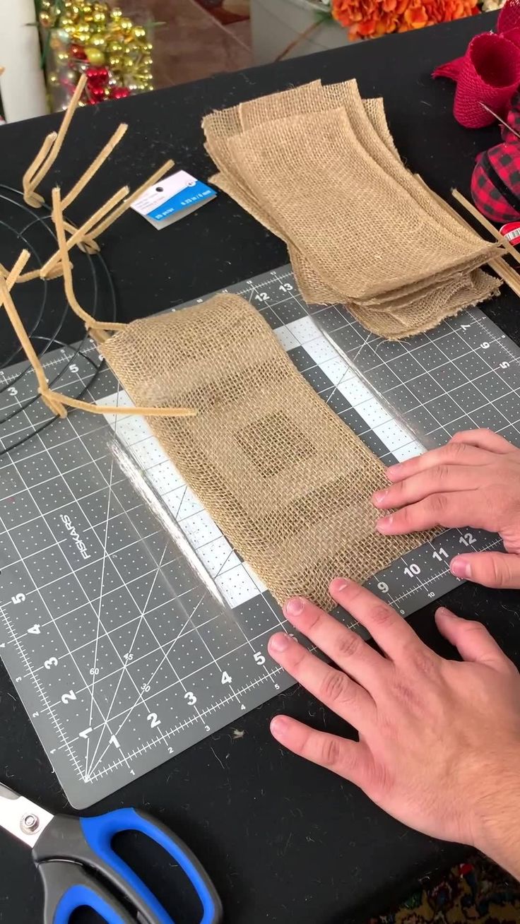 someone cutting fabric on a table with scissors and other crafting supplies next to it