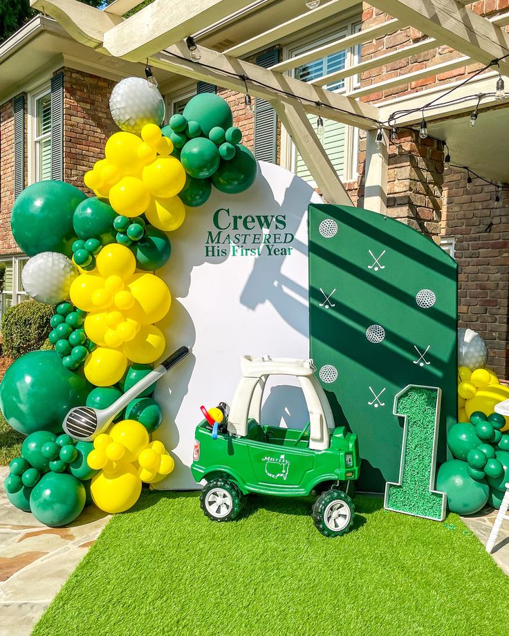 a green car parked in front of a building with balloons on the wall and decorations around it