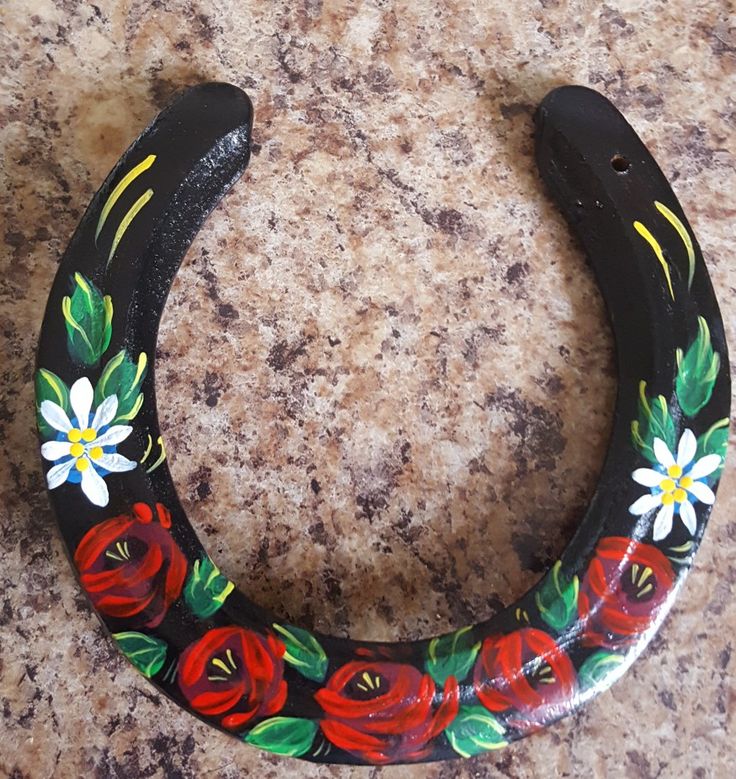 a black horseshoe with red flowers painted on it sitting on a marble counter next to a wall