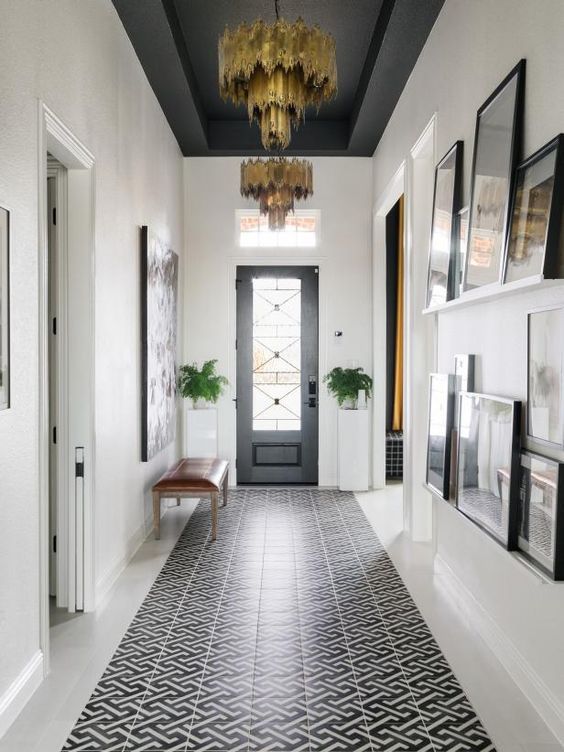 a hallway with black and white tile flooring and chandelier hanging from the ceiling