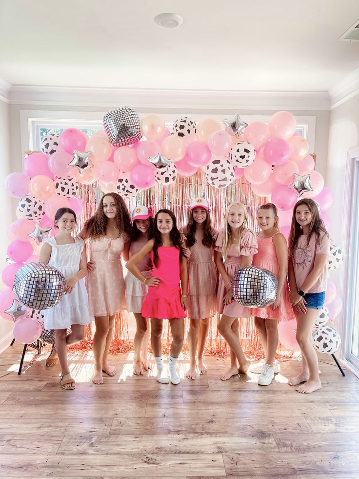 a group of young women standing next to each other in front of balloons and streamers