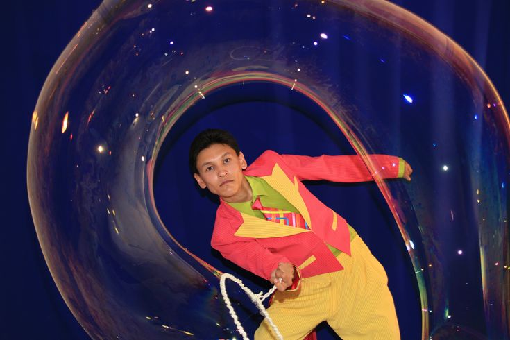 a young boy is posing in front of a giant bubble