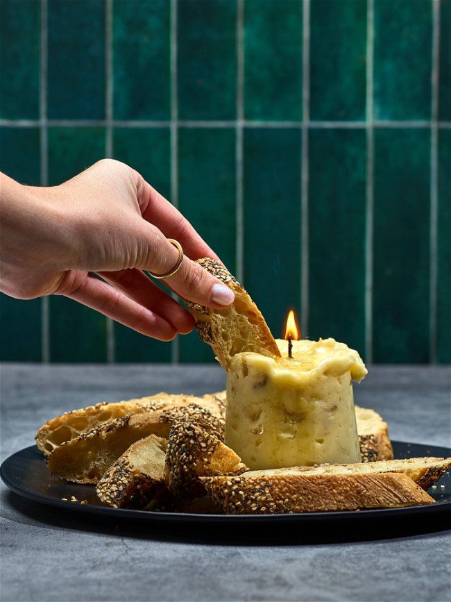 a person lighting a candle on some bread