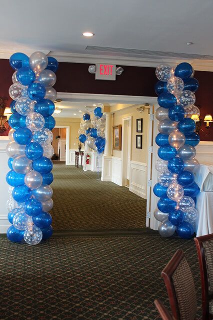 blue and white balloons are hanging from the ceiling in front of a room with chairs