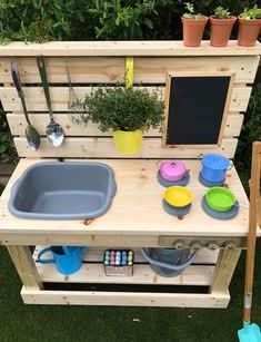 an outdoor kitchen made out of wooden pallets and potting pans with gardening tools