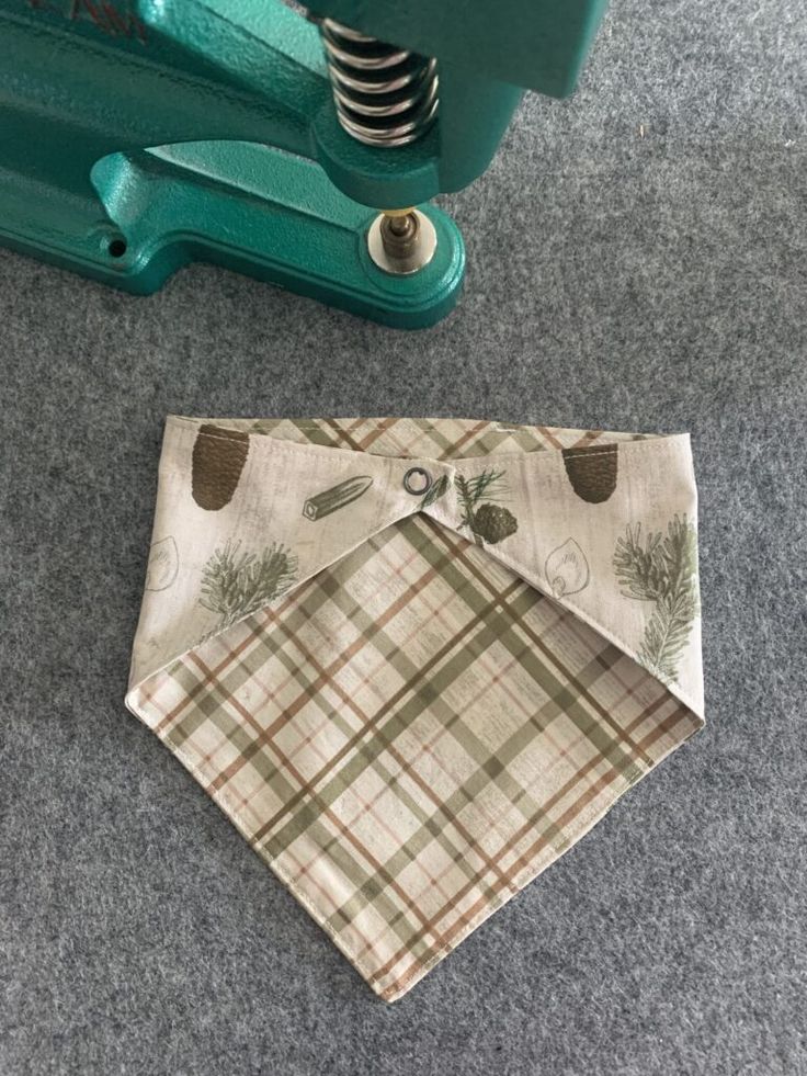 a dog bandana laying on the floor next to a piece of fabric and a green machine