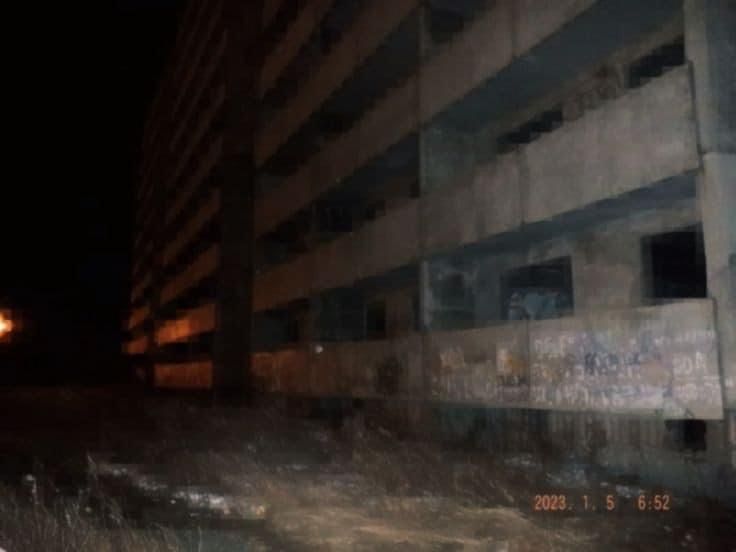 an abandoned building with graffiti on the side and street lights in the background at night