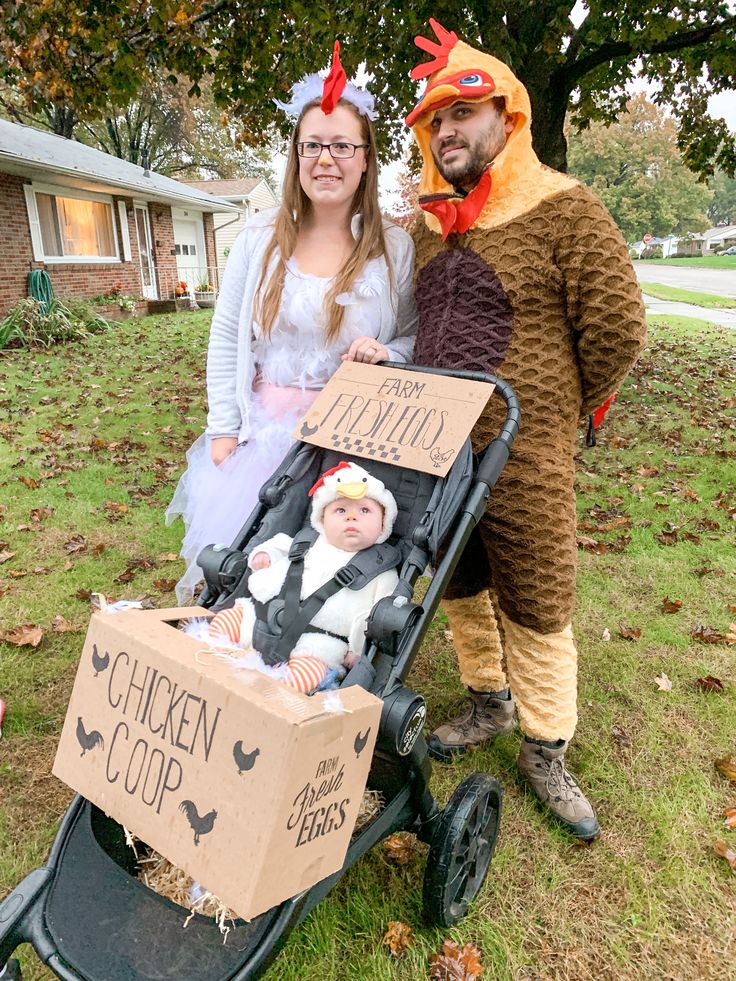 a man and woman in costumes standing next to a baby in a stroller with chickens on it