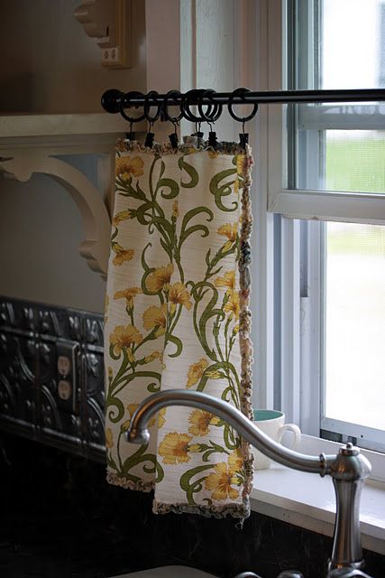 a kitchen sink with a curtain hanging from it's side next to a window