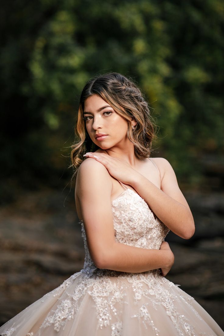 a woman in a wedding dress is posing for a photo with her hands on her chest