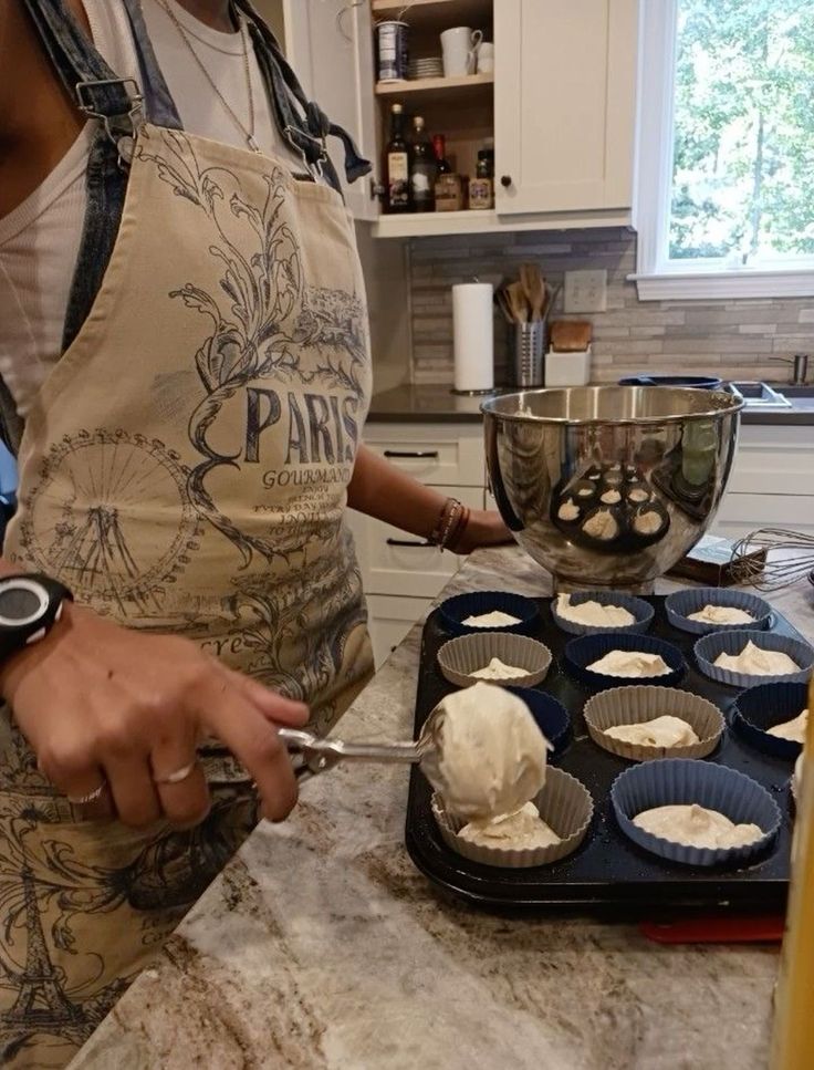 a woman is making cupcakes in the kitchen