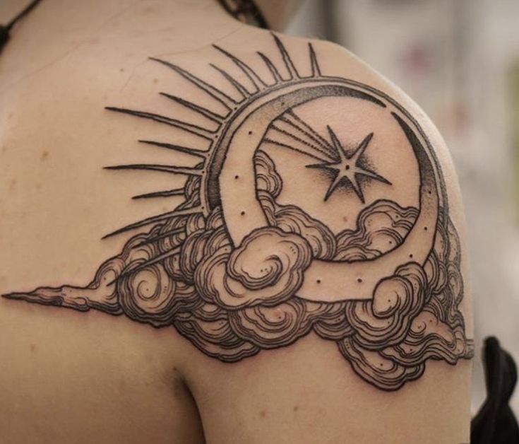 the back of a woman's shoulder with a sun and clouds tattoo on it