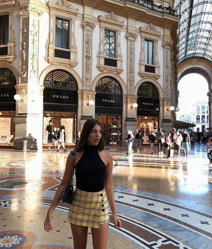 a woman standing in the middle of a mall looking at the camera with her hand on her hip