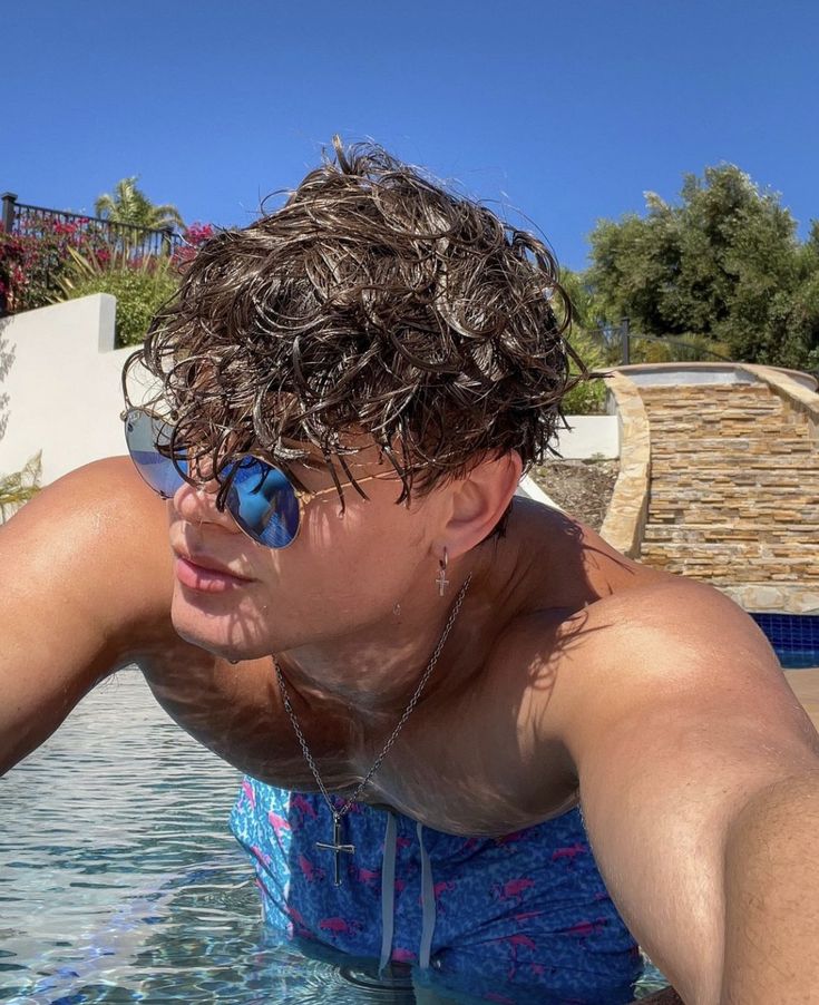 a man in the water with sunglasses on his head and one hand resting on his face