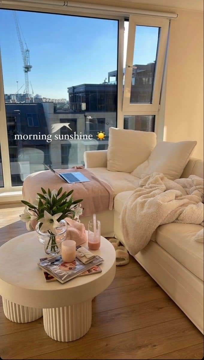 a living room filled with furniture and a large window overlooking the cityscape in the background