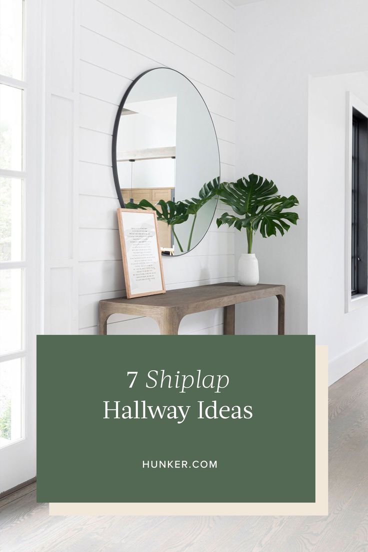 a hallway with white walls and green plants on the side table in front of it