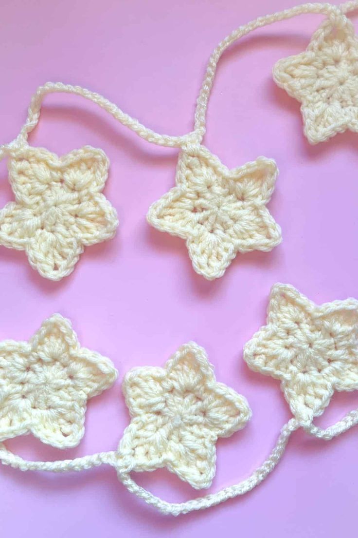 crocheted stars are arranged on a pink surface with white string attached to them