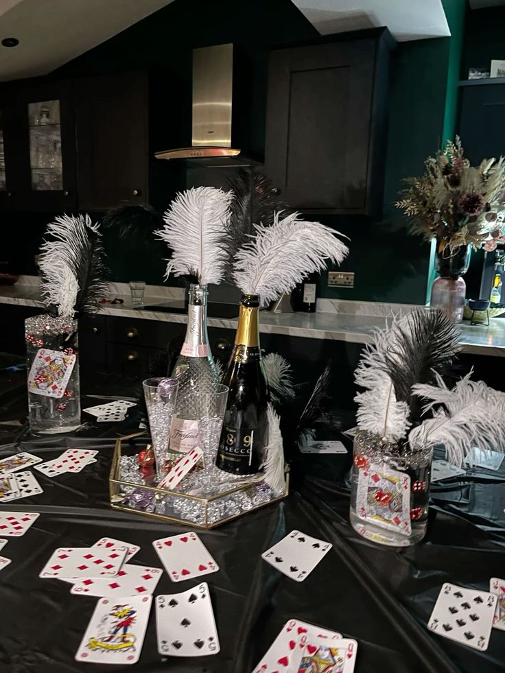 the table is set up with cards, wine bottles and vases filled with feathers