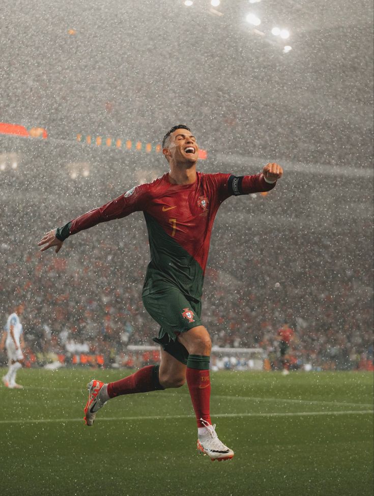 a soccer player is running in the rain with his arms wide open and eyes closed