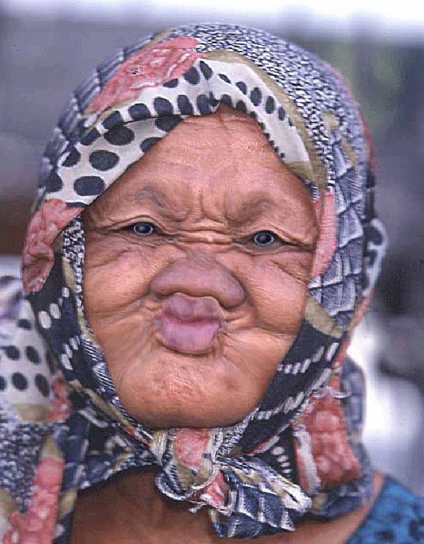 an old woman with blue and white polka dots on her head is making a funny face