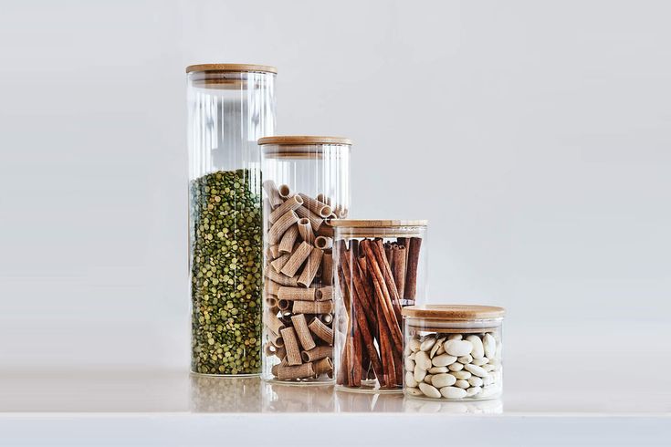 several glass containers filled with different types of spices and herbs on a white table top