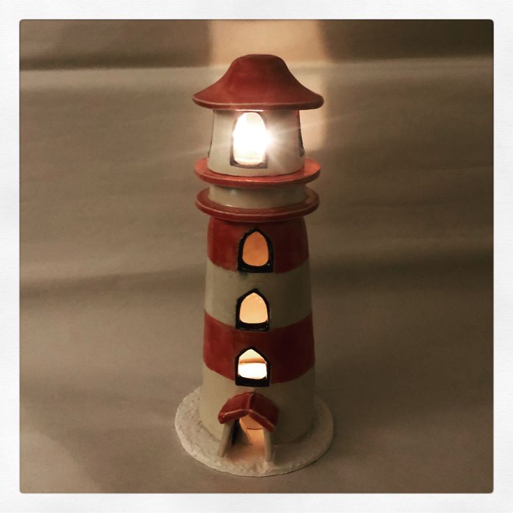 a red and white lighthouse with a light on it's top is lit up