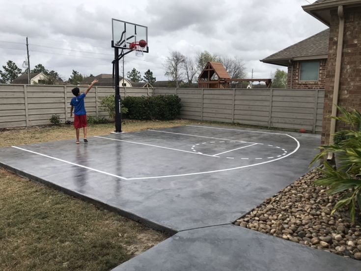 a young boy is playing basketball on an outdoor court in the backyard with his hands up