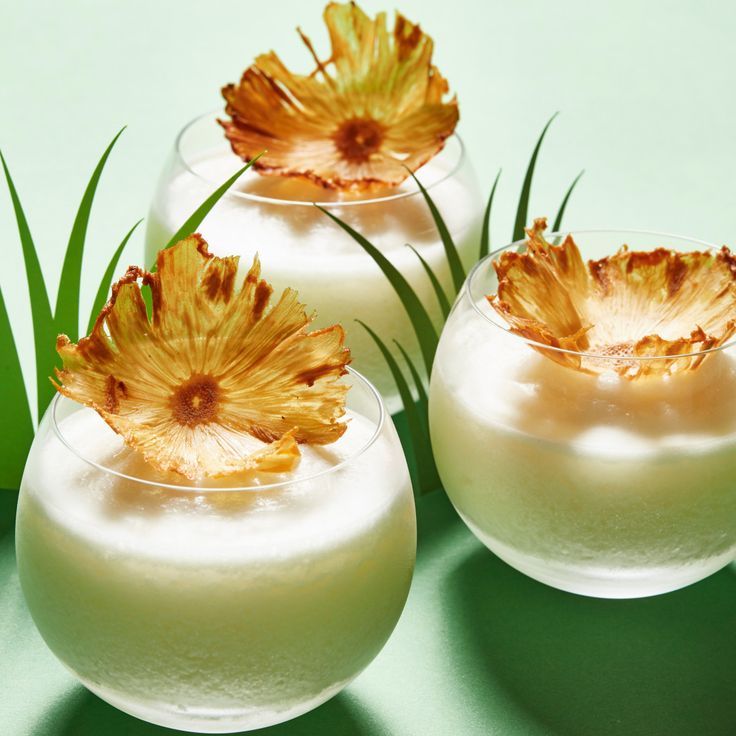 three glasses filled with white liquid and flowers