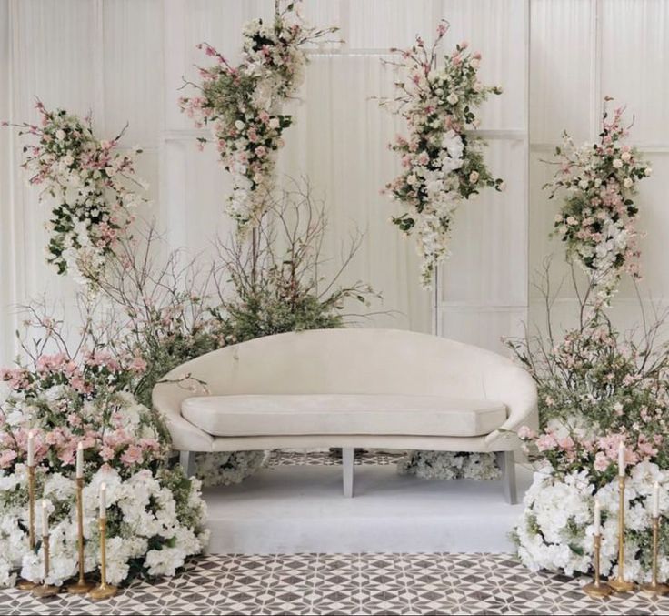 a white couch surrounded by flowers and greenery