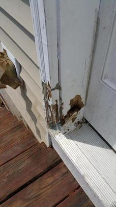 an open door with peeling paint on the outside and wood flooring in front of it