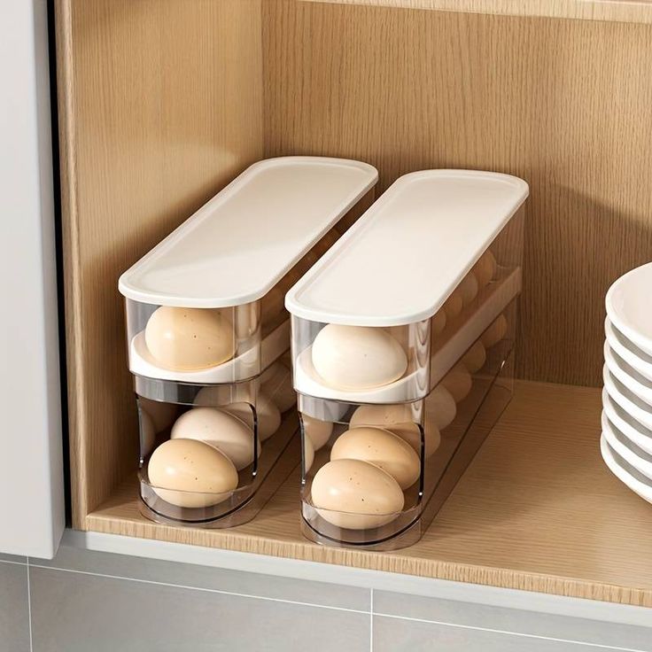 there are three containers with eggs in them on the shelf next to plates and bowls