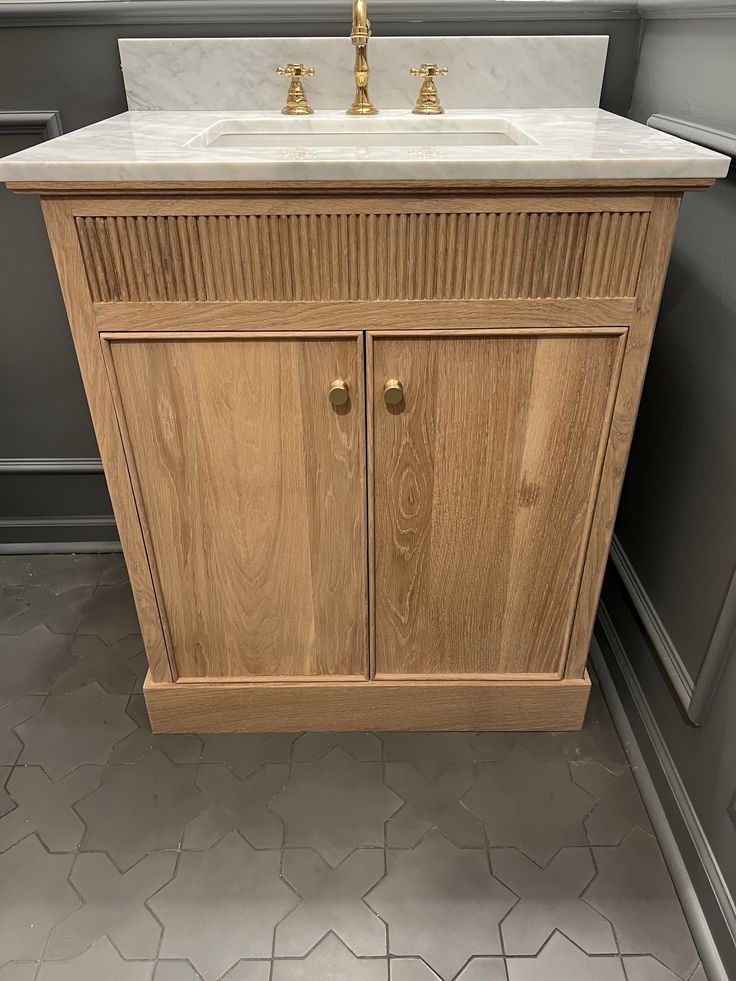 a bathroom vanity with marble top and wooden cabinet