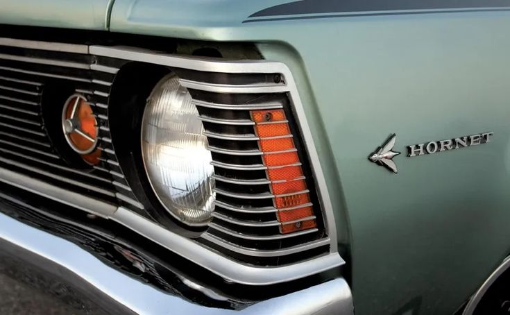 the front end of an old, green truck with chrome grills and orange lights