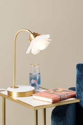 a table with a lamp on it next to a blue chair and a glass vase