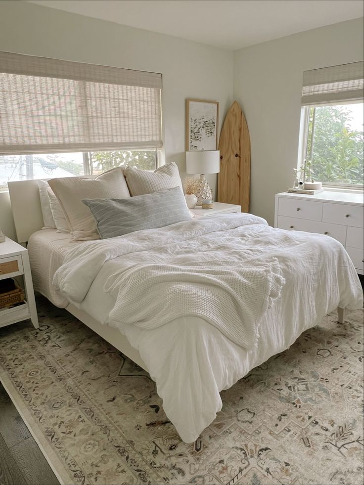 a white bed sitting in a bedroom next to two windows