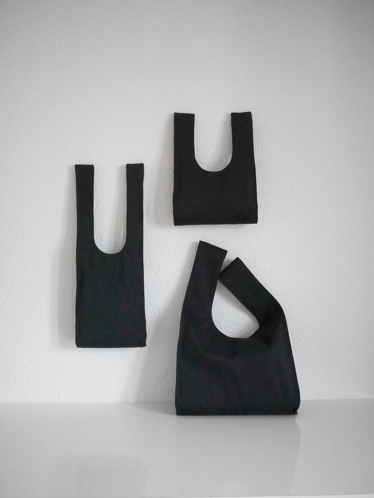 three black bags hanging on the wall next to each other, one with a hole in it