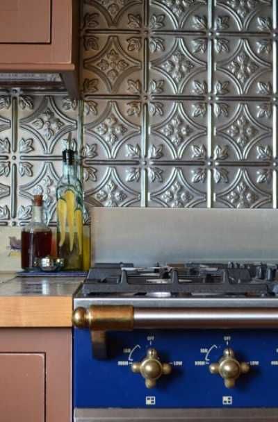 a blue stove top oven sitting inside of a kitchen next to wooden cabinets and counter tops